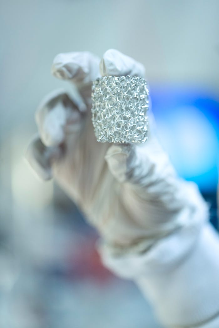 Close-up of a scientist holding metallic foam in a lab setting, highlighting innovation.